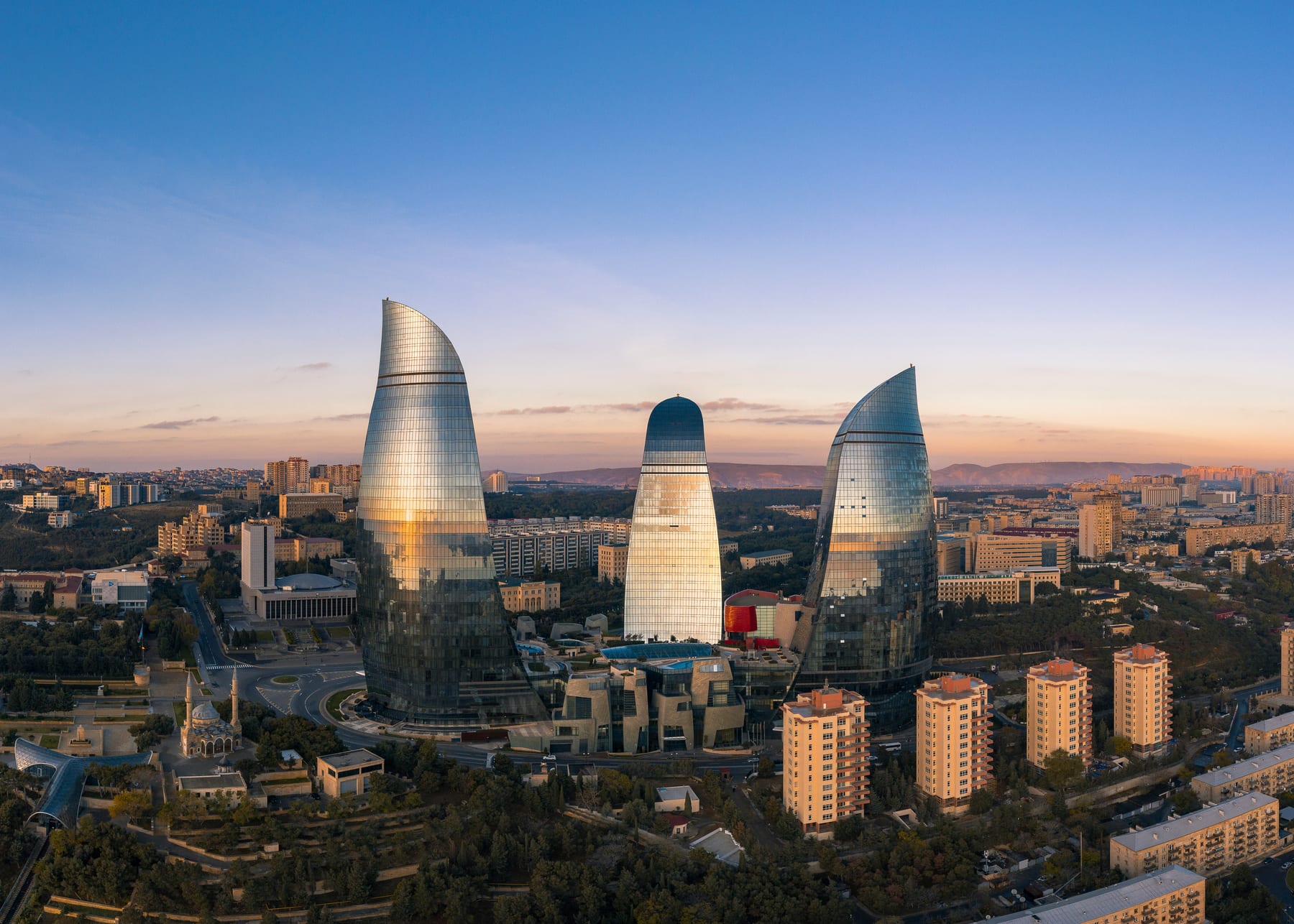 Tri sklenené Flame Towers nad mestskou panorámou Baku pri teplom večernom svetle