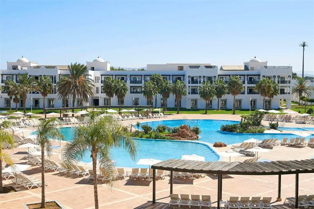 Bazén obklopený palmami a bielymi budovami rezortu Iberostar Waves Saïdia v Maroku