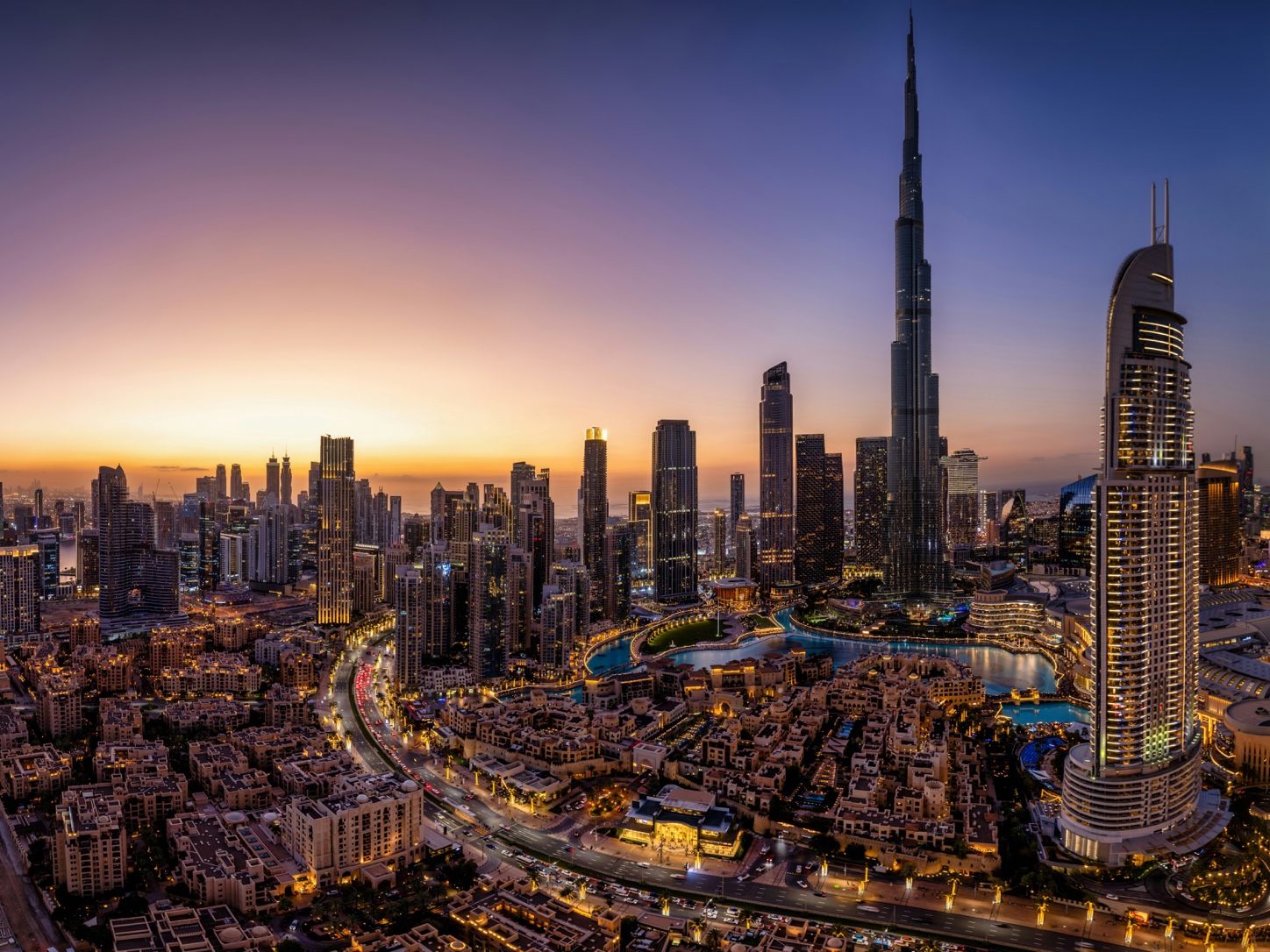 Downtown Dubai kivilágított panorámája a Burj Khalifával napnyugtakor